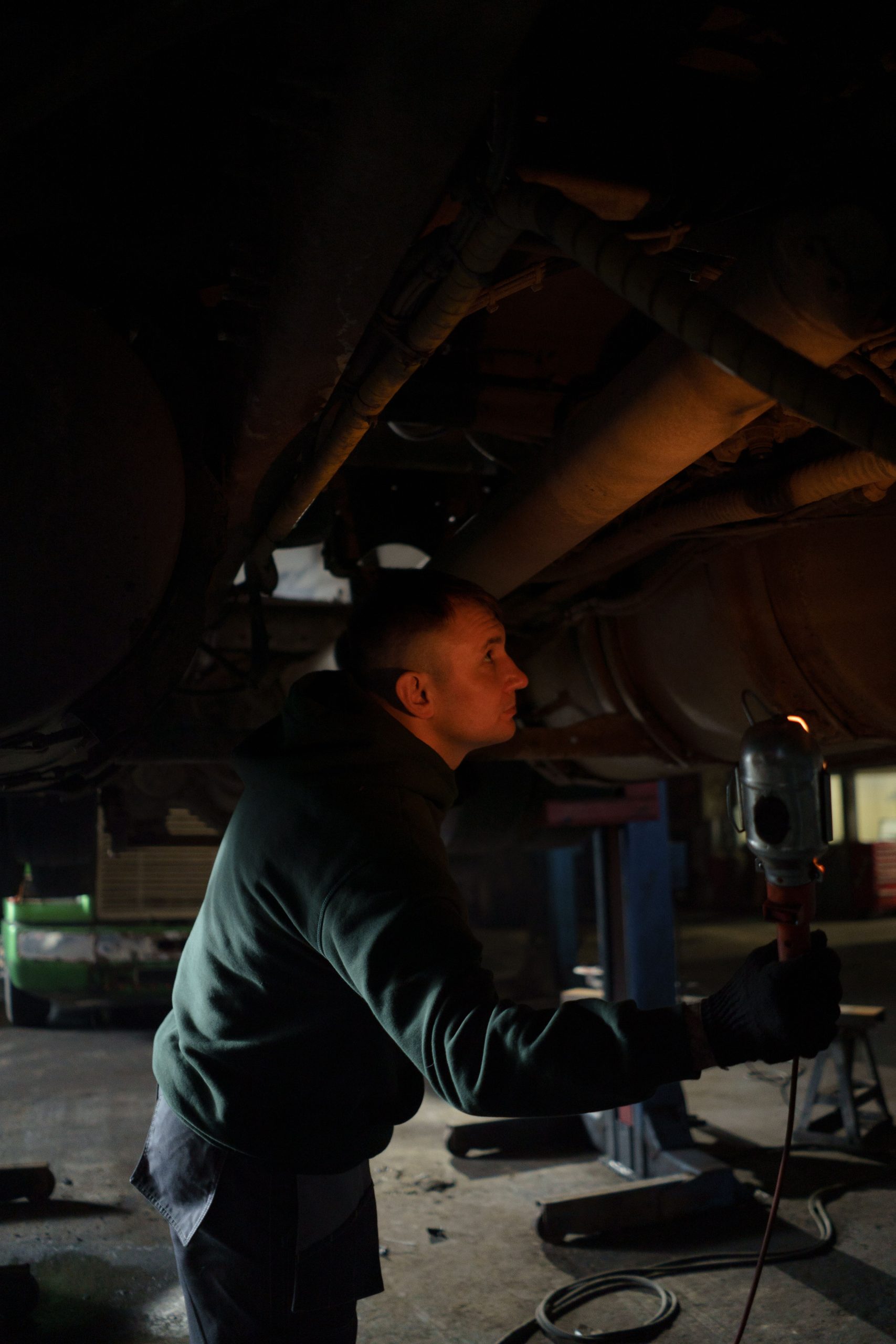 A mechanic inspects the underbody of a vehicle in an auto repair shop.